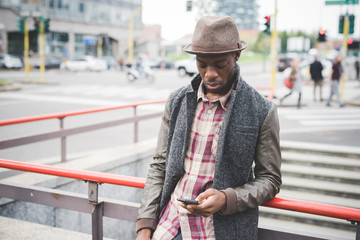 Young handsome afro black man leaning on a handrail, using smart phone hand hold - technology, social network, communication concept