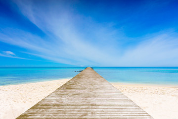 Long wooden bridge in Beautiful beaches, crystal clear sea and blue sky with a cloudy.