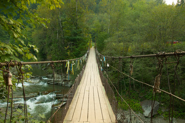 Suspension hanging bridge over mountain river in the forest