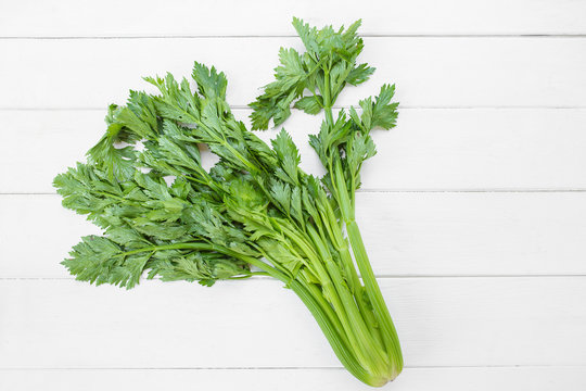 Celery on wooden white table background.