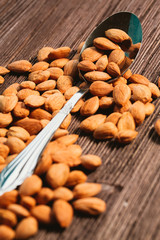 apricot kernels sprinkled with metal spoon on a wooden background