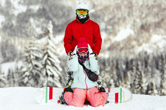 Couple in colorful ski suits poses on the hill somewhere in the mountains