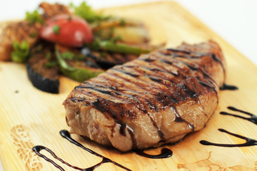 Pork steak with grilled vegetables on a wooden board