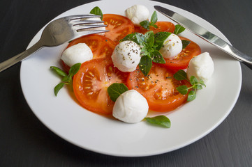 Caprese salad with ripe tomatoes and mozzarella with fresh Basil leaves. Italian food.
