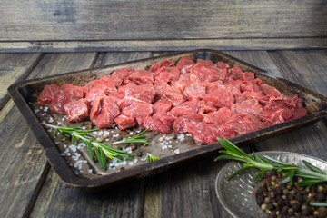 Raw meat with salt, pepper and rosemary on the baking pan