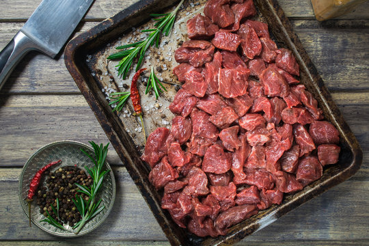 Raw meat with salt, pepper and rosemary on the baking pan