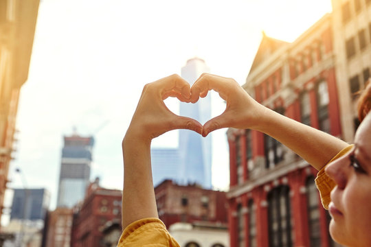 Young female tourist making heart hands in front of One World Trade Centre, Manhattan, New York, USA