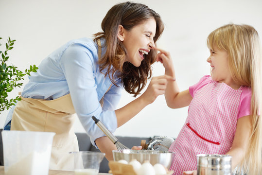 Mother and daughter baking together, fooling around