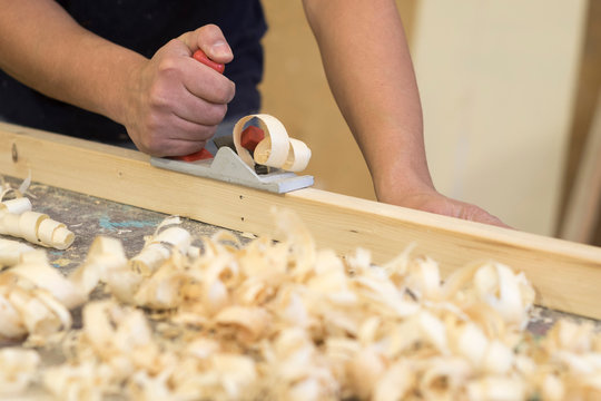Hand of male carpenter using wood plane in workshop