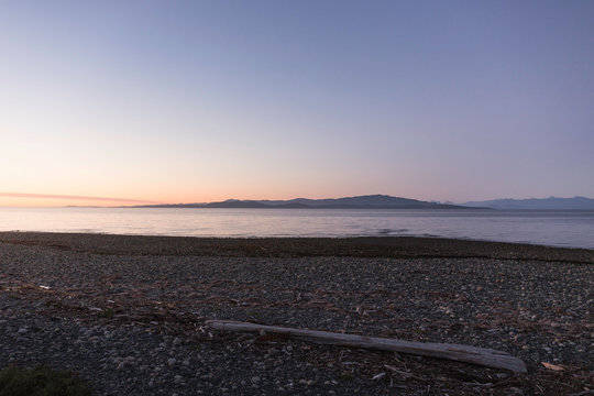 Driftwood log on beach at dusk, Rathrevor Beach Provincial Park, Vancouver Island, British Columbia, Canada