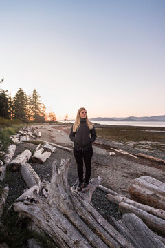 Woman gazing from driftwood log at Rathrevor Beach Provincial Park, Vancouver Island, British Columbia, Canada