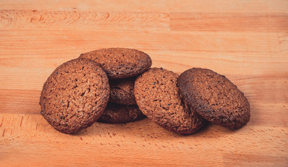 Homemade oat cookies on a wooden background. Oatmeal cookies on a old wooden cutting board. Freshly baked oatmeal raisin cookies on rustic wood table. Closeup from above with natural lighting.