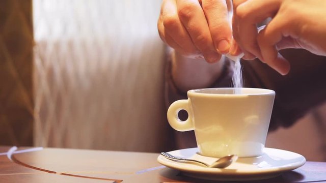 Cropped view of Man taking and pours sugar from the sticker on cup of tea