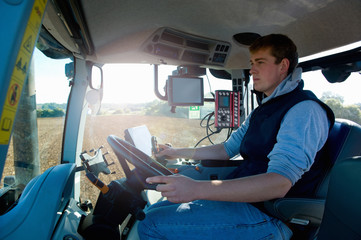 Young man driving tractor using global positioning system