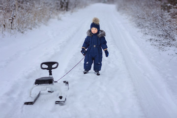 Fototapeta na wymiar Little boy outdoor. Winter. Sled..