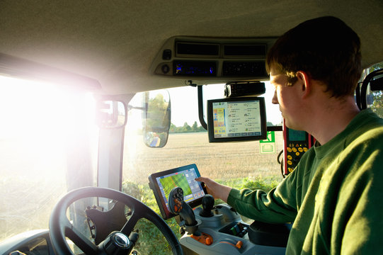 Young man driving tractor using touchscreen on global positioning system