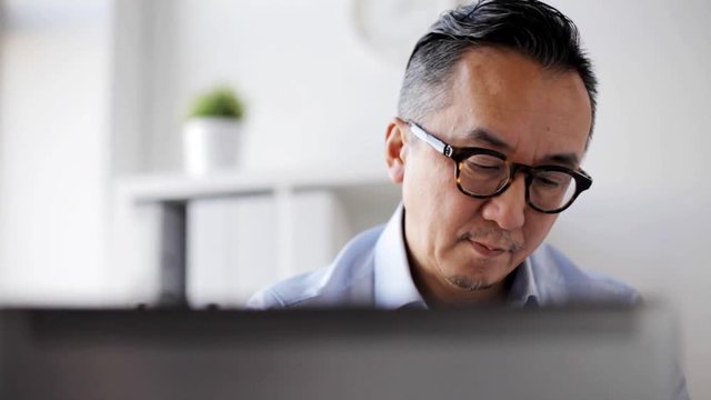 businessman in eyeglasses with laptop at office