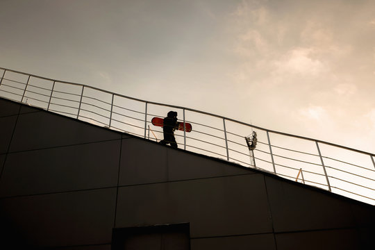 Boy carrying snowboard down steps at ski slope