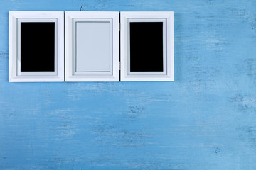 Blank photo frames on blue wood background. Painted scraped wooden board. Grunge plywood texture or pattern.