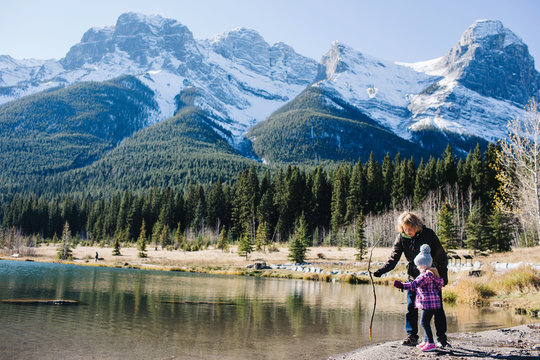 Grandmother and granddaughter beside river, Three Sisters, Rocky Mountains, Canmore, Alberta, Canada