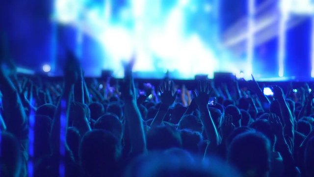 Crowd of excited fans applauding to popular band performing favorite song