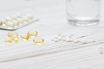  White and yellow pills in a jar on a white wooden background