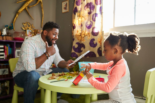 Father And Daughter Enjoying Colouring In Activity