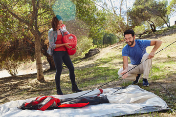 Mid adult couple camping, erecting their tent