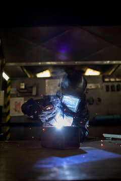 Female metalsmith welding metal box on workbench