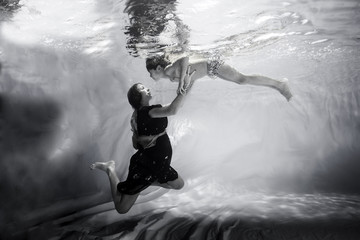 mother takes the hands of her son underwater