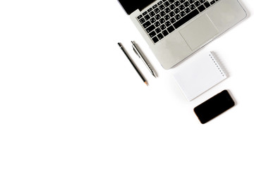 Empty copyspace in left corner and center. Minimalistic workplace with laptop keyboard, smartphone, notebook, pen and pencil on white background. Flat lay