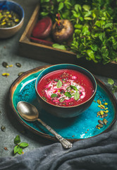 Spring detox beetroot soup with mint, chia, flax and pumpkin seeds in blue ceramic bowl over grey...