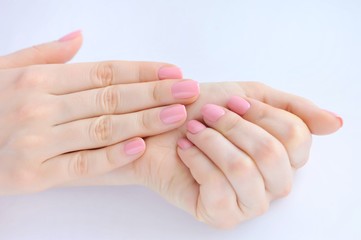 Closeup of hands of a young woman with pink manicure on nails
