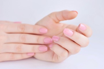 Closeup of hands of a young woman with pink manicure on nails