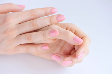Closeup of hands of a young woman with pink manicure on nails