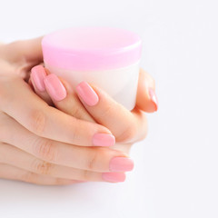 Hands of a woman with pink manicure with cream