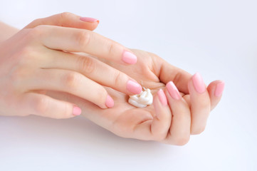 Young woman with pink manicure applies cream on her hands