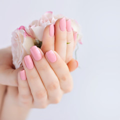 Hands of a woman with pink manicure on nails and roses