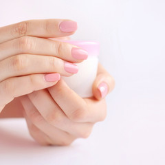 Hands of a woman with pink manicure with cream