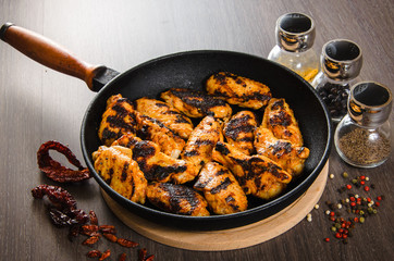 grilled chicken wings in grill panwith spices, wooden background