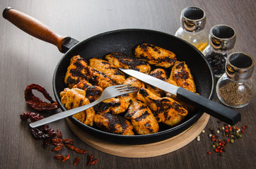 grilled chicken wings in grill panwith spices, wooden background