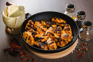 grilled chicken wings in grill panwith spices, wooden background
