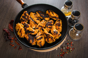 grilled chicken wings in grill panwith spices, wooden background