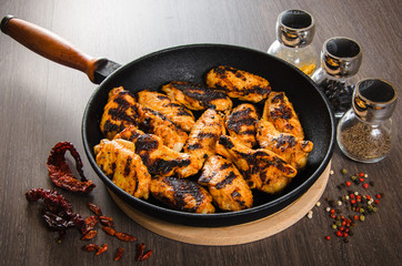 grilled chicken wings in grill panwith spices, wooden background