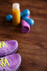 Fitness gym equipment. Sneakers, dumbbells with towel. Fresh orange juice drink. Workout footwear. Sport trainers on grunge rustic wood background.