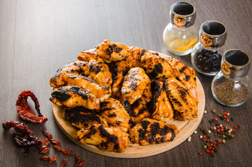 grilled chicken wings in grill panwith spices, wooden background