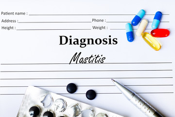 Mastitis - Diagnosis written on a piece of white paper with medication and Pills
