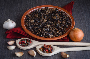 Roasted mushrooms with spices on plate, wooden background