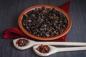 Roasted mushrooms with spices on plate, wooden background
