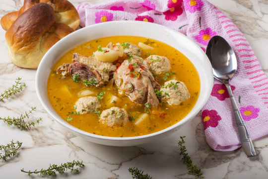 Meatballs soup with chicken meat and herbs in white bowl with spoon
